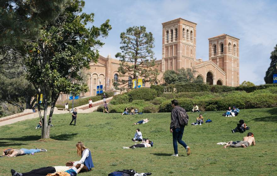 Students lounge and walk across the green on a sunny day at the UCLA campus; Royce Hall in the background