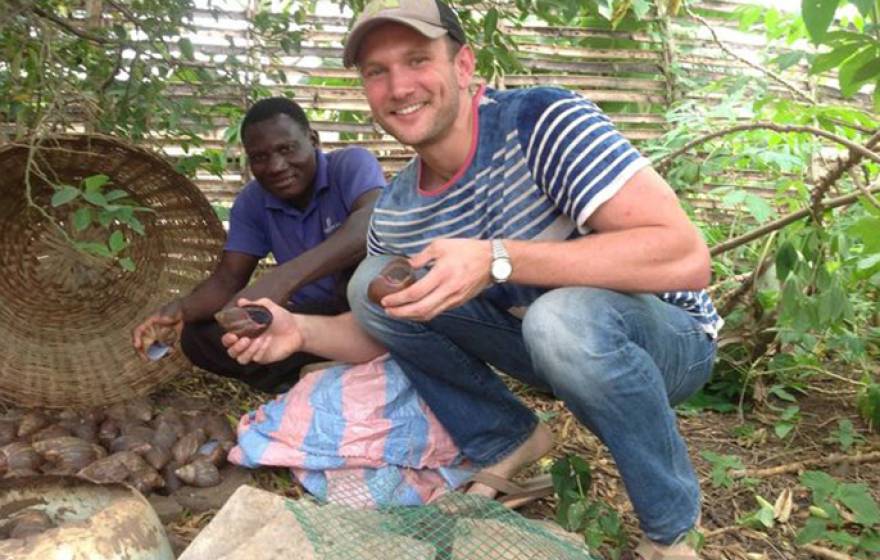 UCLA senior Grant Guess (right) and farmer Thomas Bodzrenou hold giant land snails that will be bred, raised and sold to local markets and restaurants. The snails are the latest venture that Guess has launched to benefit a school for children with disabil