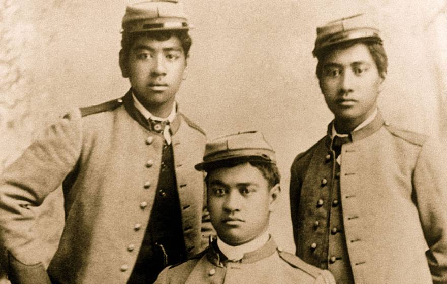 A sepia-toned historical portrait of three young Hawaiian men wearing military uniform