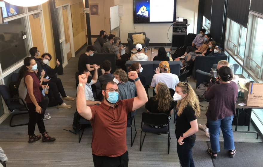 Astronomers cheering and gathered together to look at the James Webb Telescope images