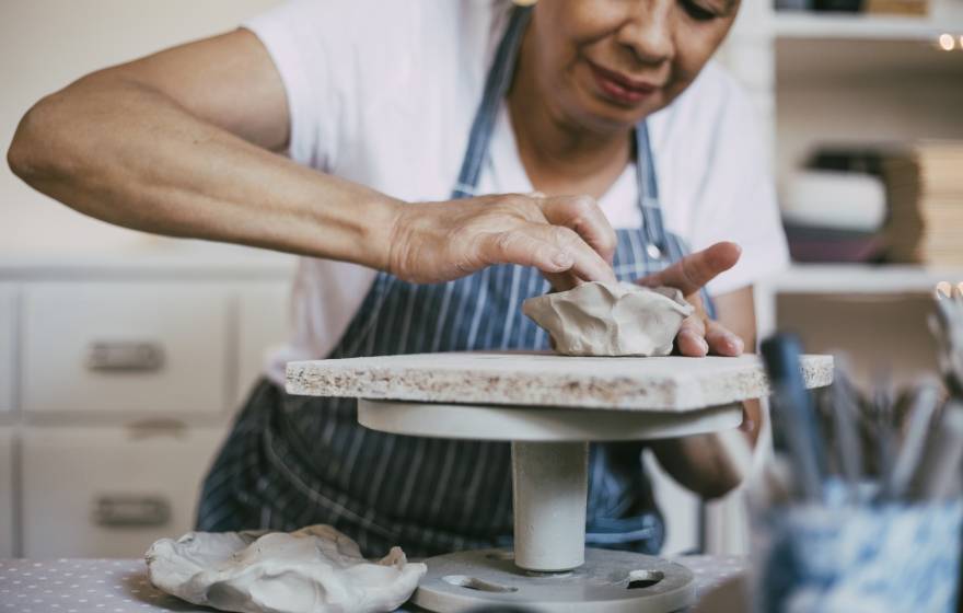 A person wearing an apron working at a ceramics wheel