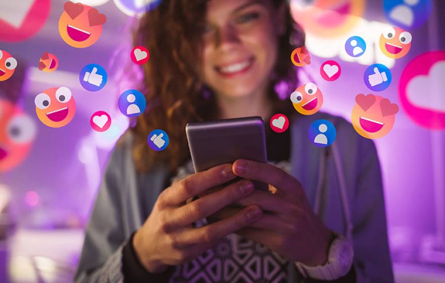 Happy young woman using her phone with emojis surrounding her