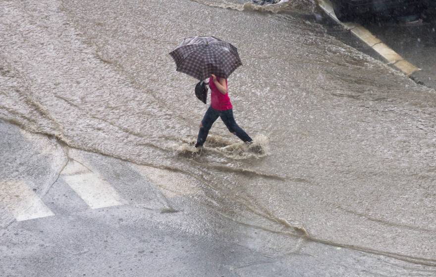Woman walking through a flooded road with an umbrella