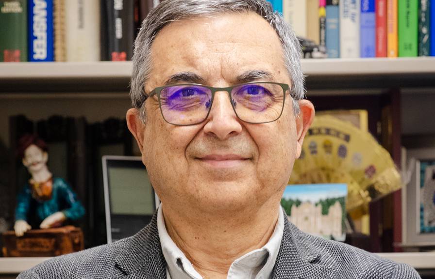 Man with glasses in front of bookshelf Ahmet Palazoglu