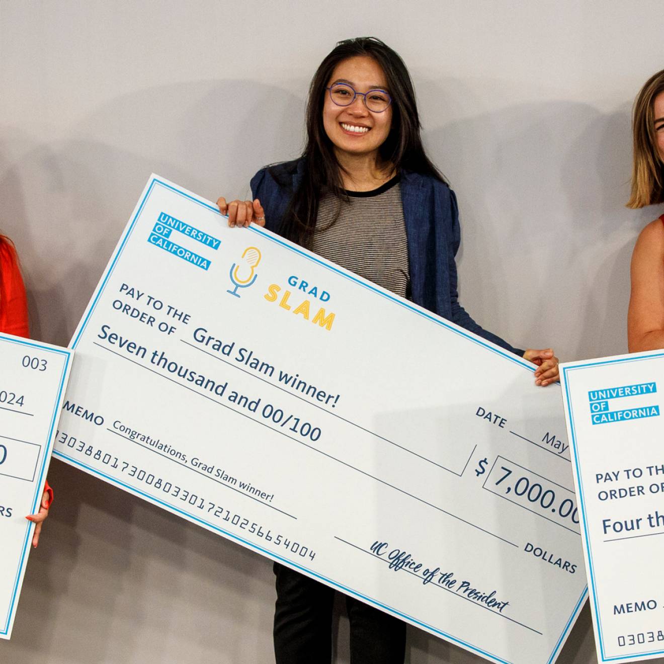 Three women posing with giant checks