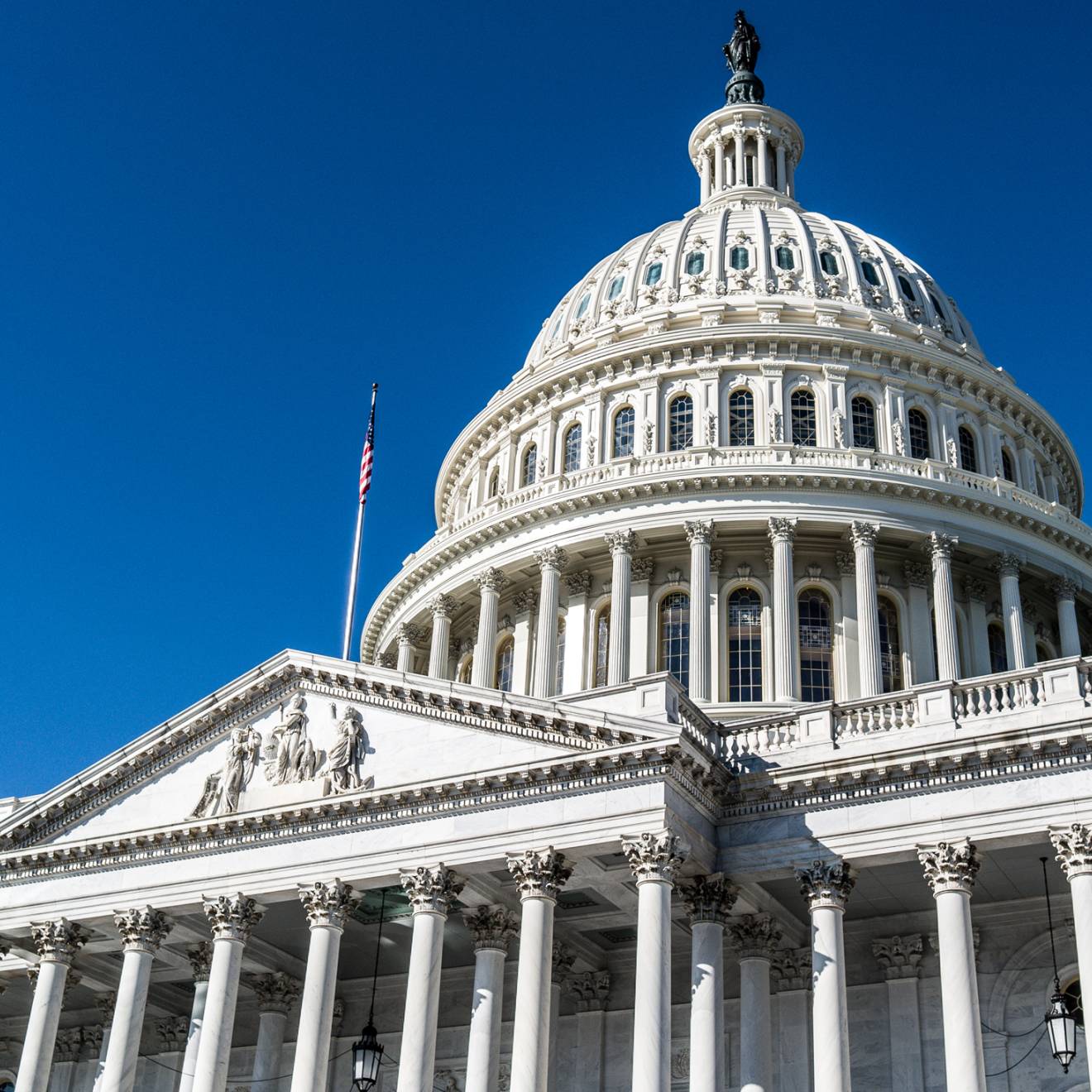 The U.S. Capitol building viewed from an angle against a bright blue sky