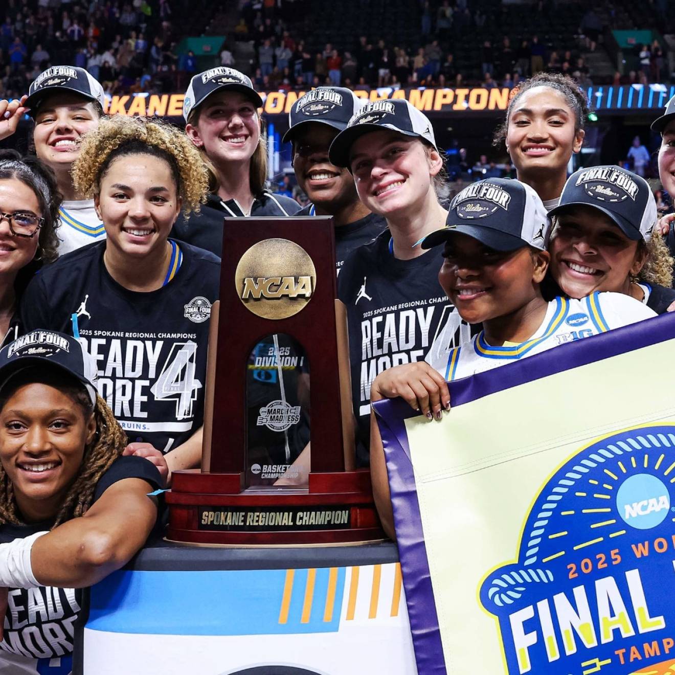 The UCLA women's basketball team in Final Four gear smiles for a group picture around the Spokane regional trophy