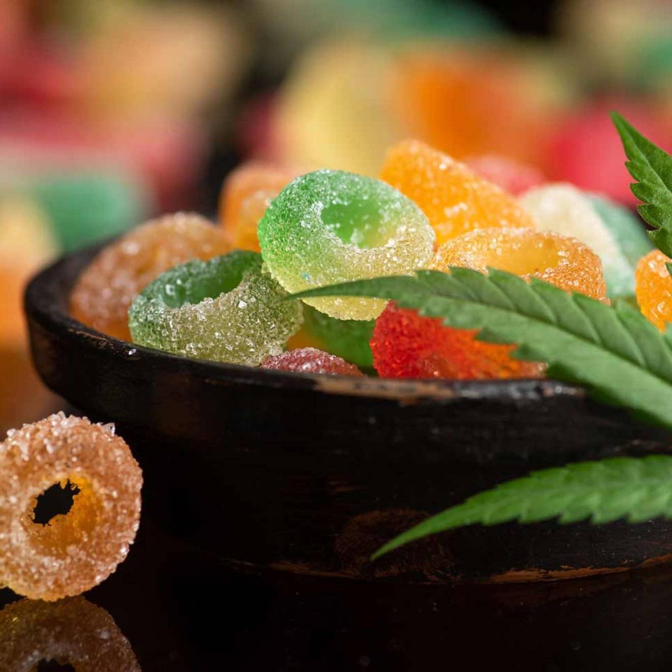 A bowl of gummies with a marijuana leaf draped over it