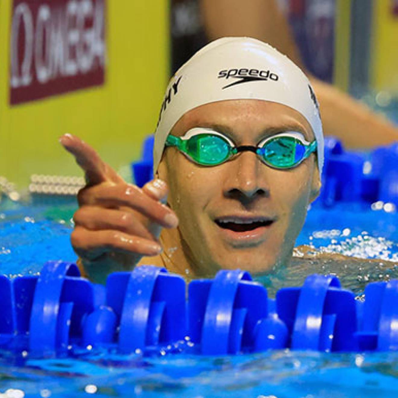 Ryan Murphy pointing from the pool in cap and googles just after a race