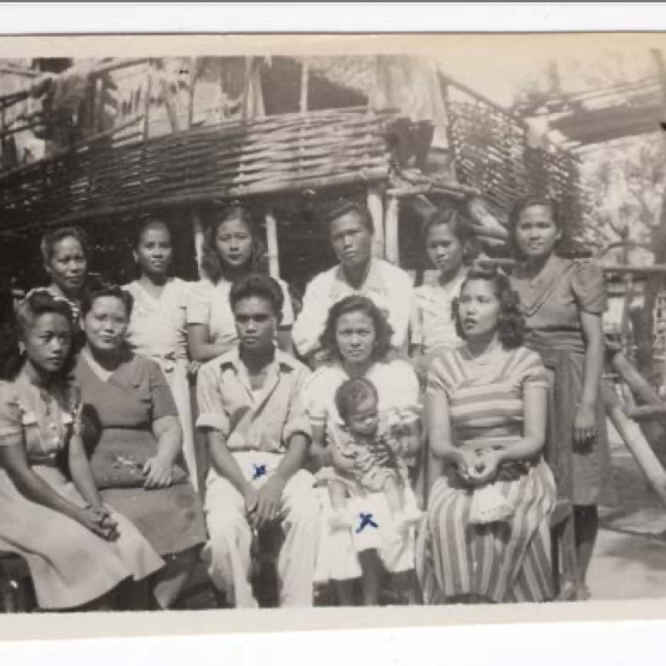 In an old black-and-white photo, a family poses outside
