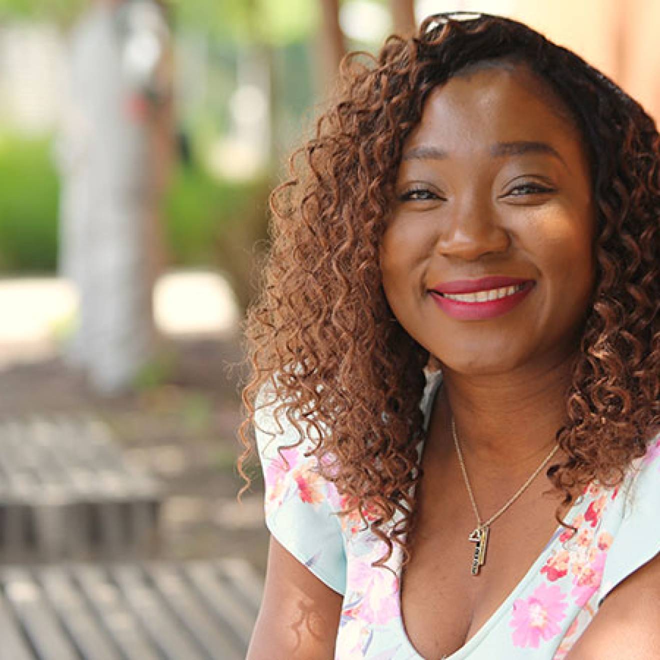 A woman smiles for a portrait, sitting on a bench