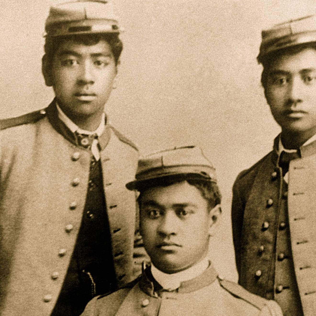 A sepia-toned historical portrait of three young Hawaiian men wearing military uniform