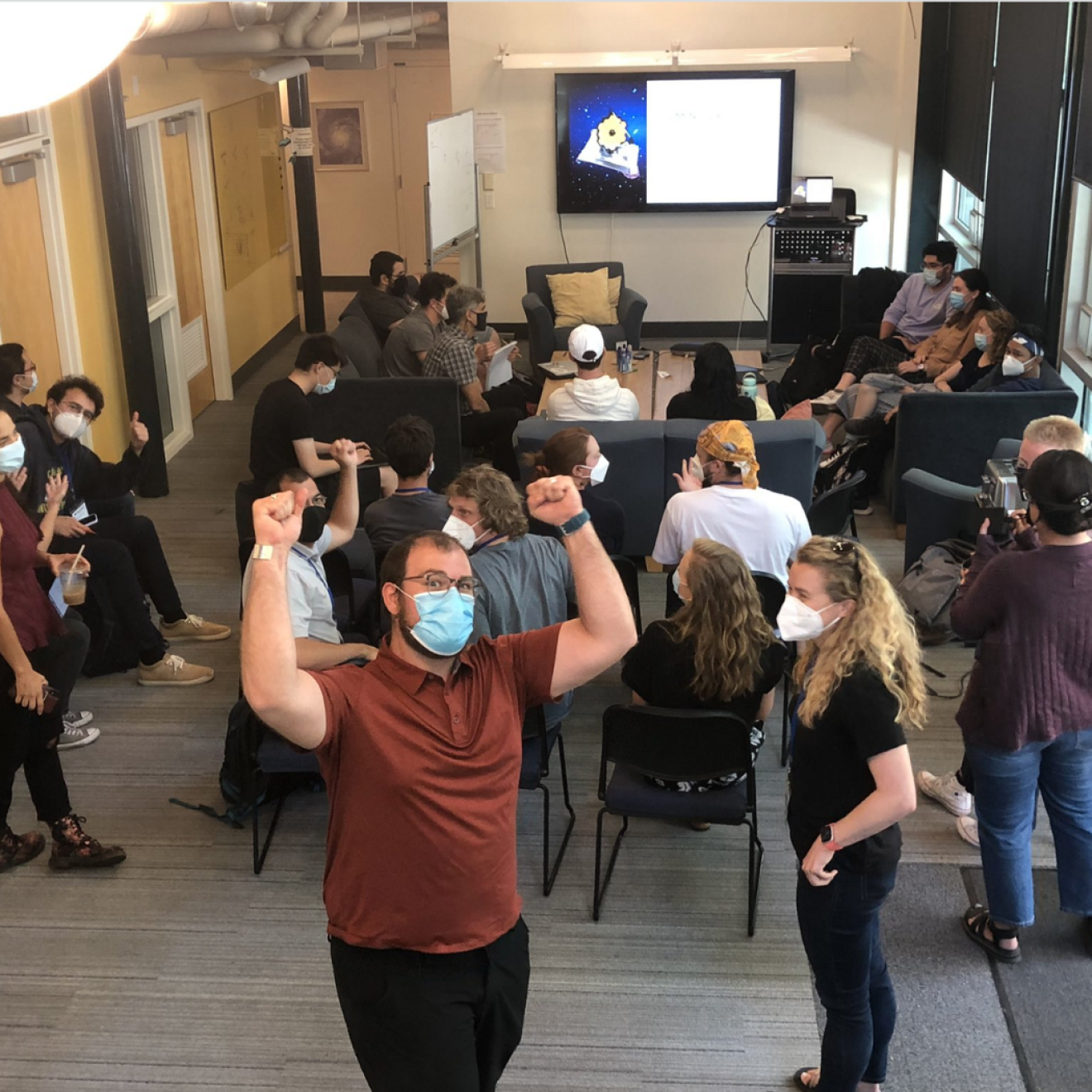 Astronomers cheering and gathered together to look at the James Webb Telescope images